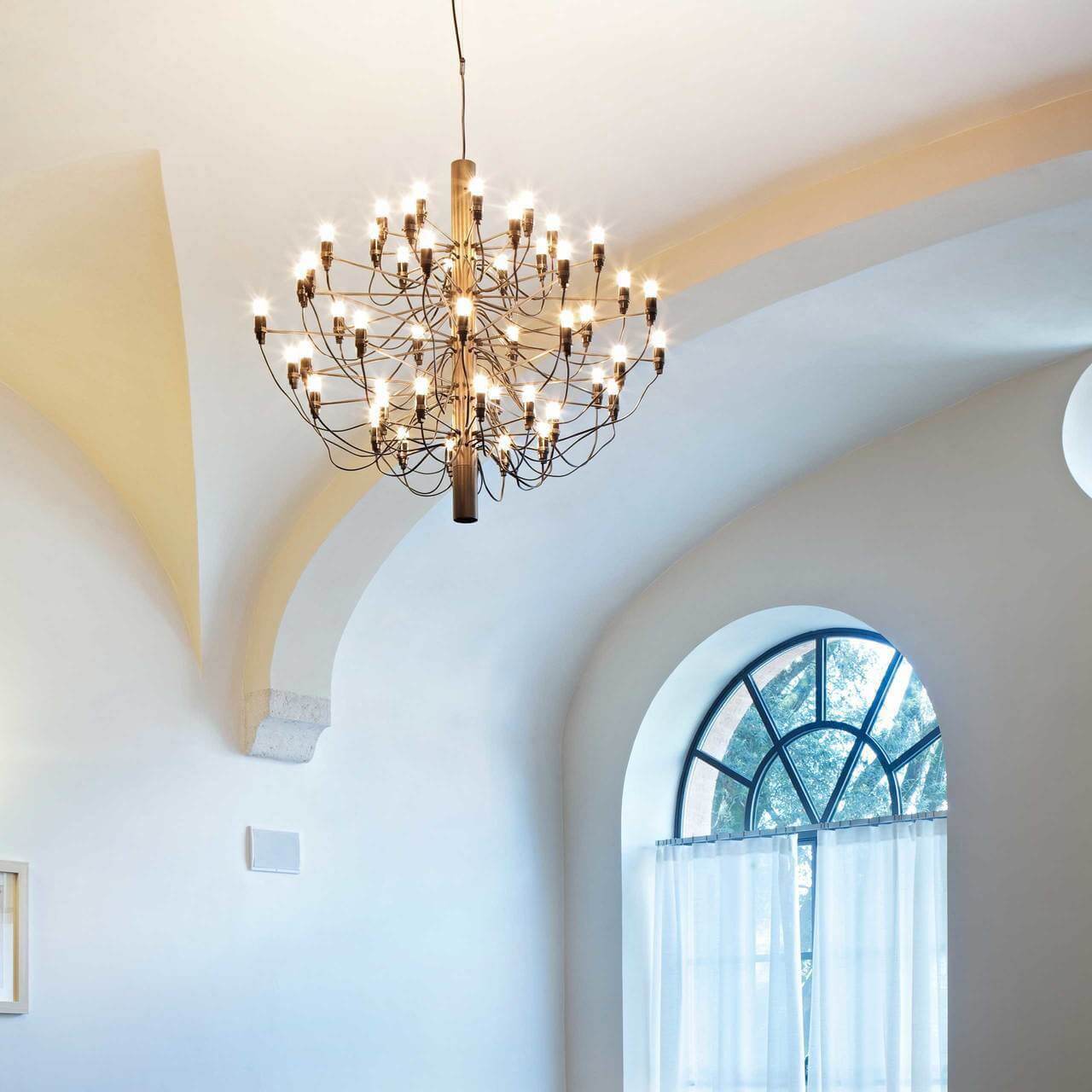 Elegant dining room illuminated by a matte black metal tiered chandelier, creating a dramatic atmosphere