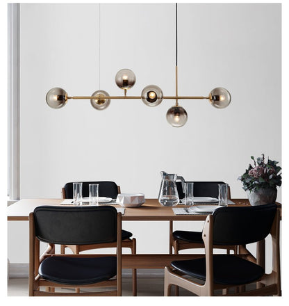 Linear design of the brass chandelier with varied glass orbs