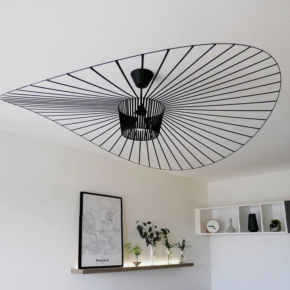 Winding silhouette of a large black pendant light from an angle